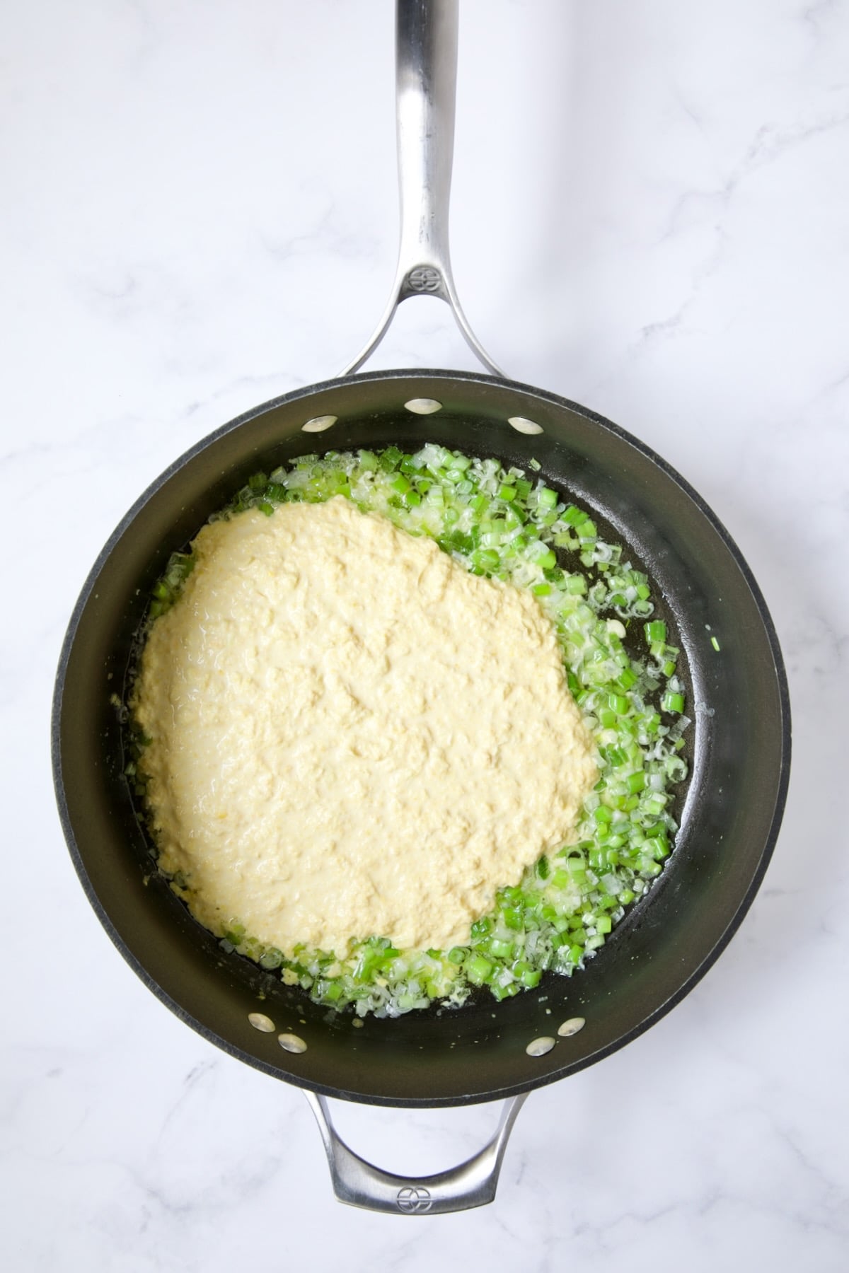 Scallions and pureed corn in nonstick skillet.