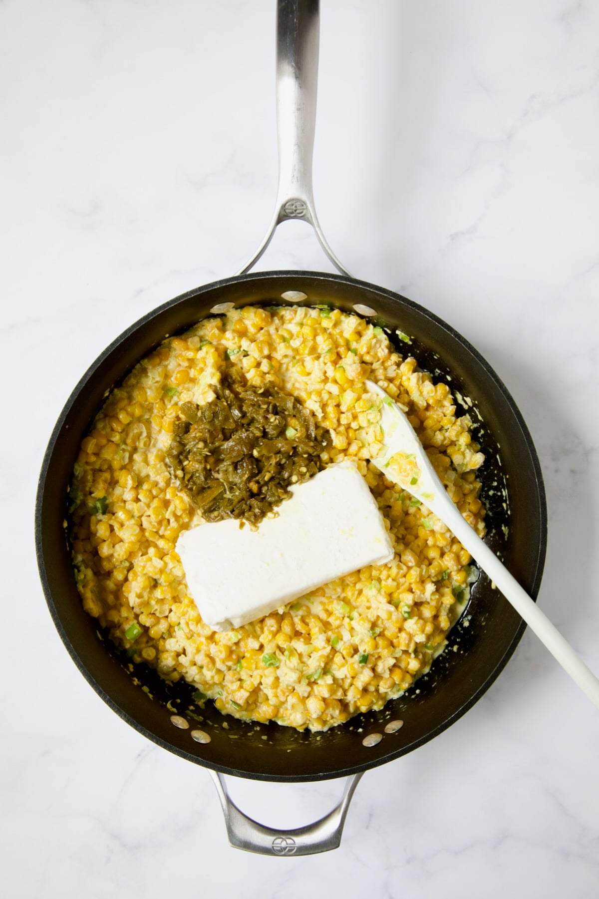 Corn in nonstick skillet with green chiles and cream cheese added before they're stirred in.