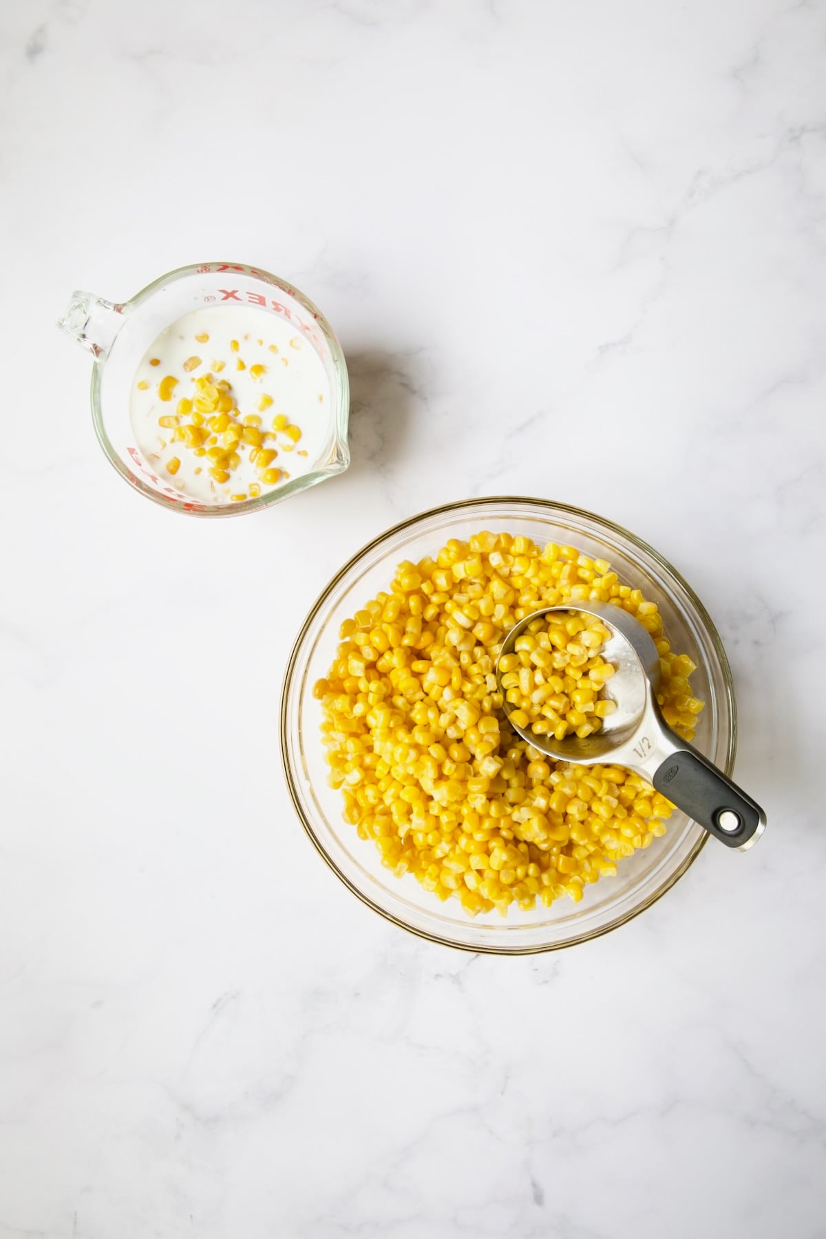 Corn in glass bowl with some in glass measuring cup added to milk.