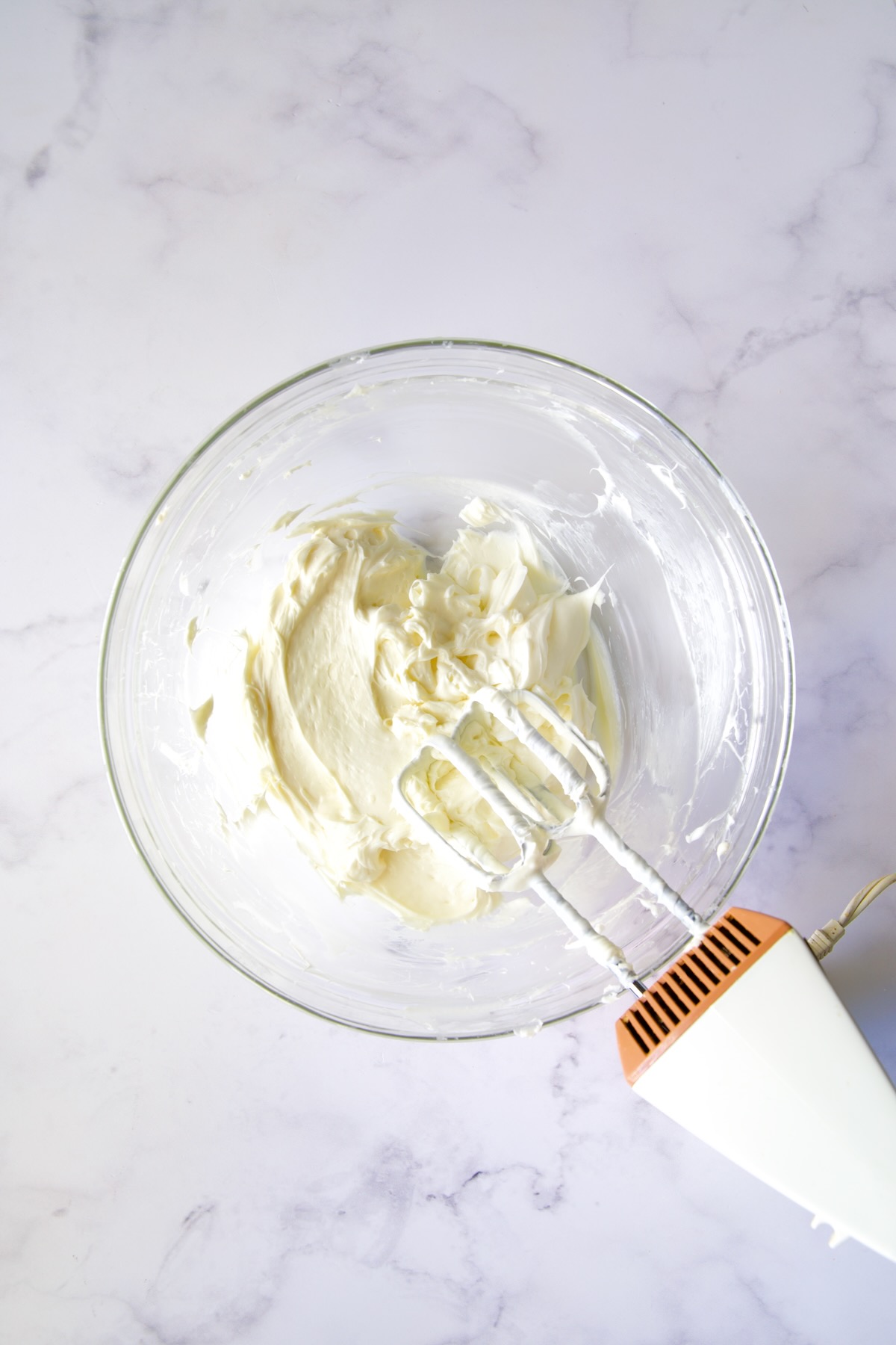Cream cheese and powdered sugar blended together to smooth consistency in glass bowl.