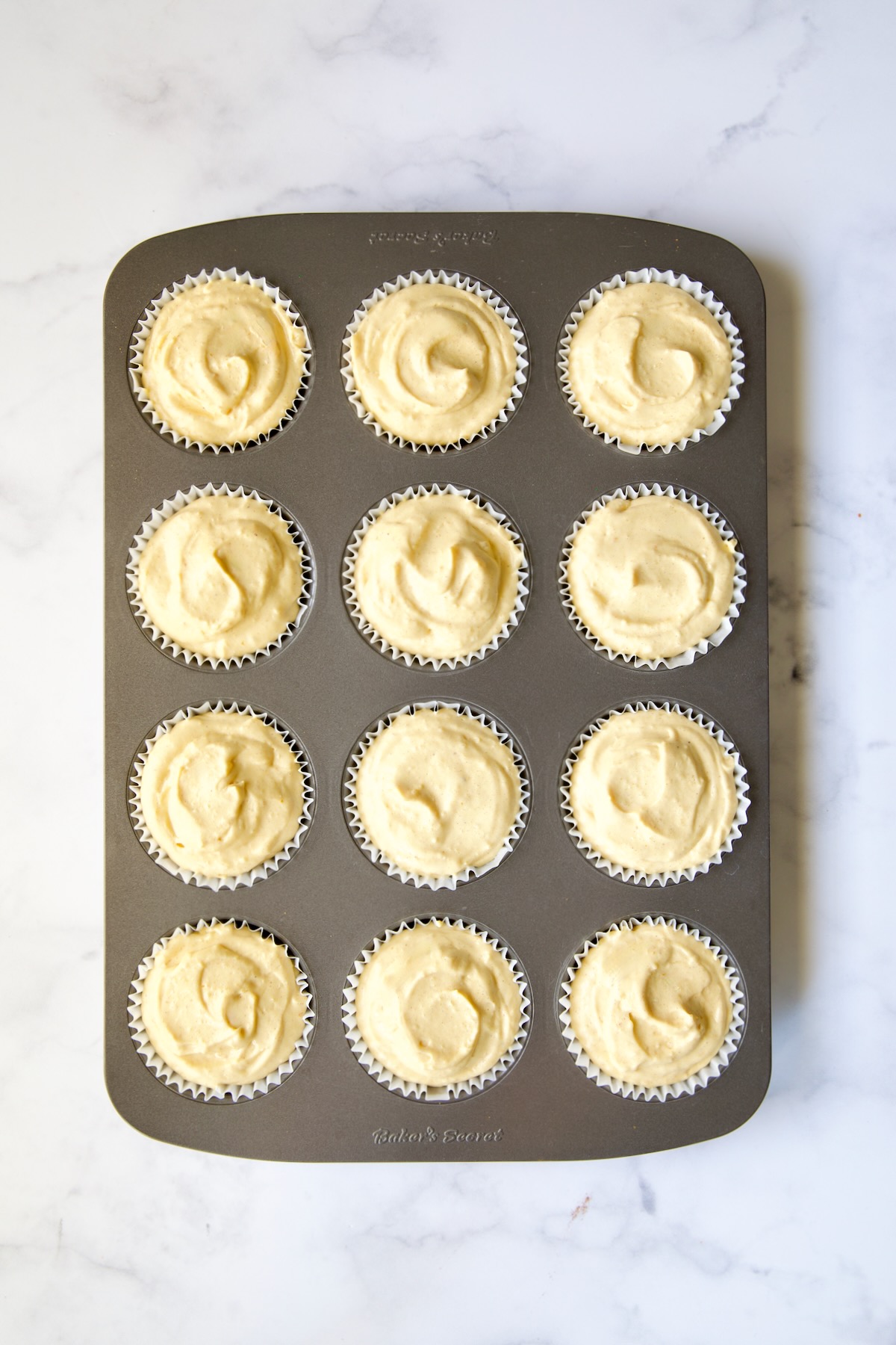 Muffin pan with cheesecake filling in each of the cups.