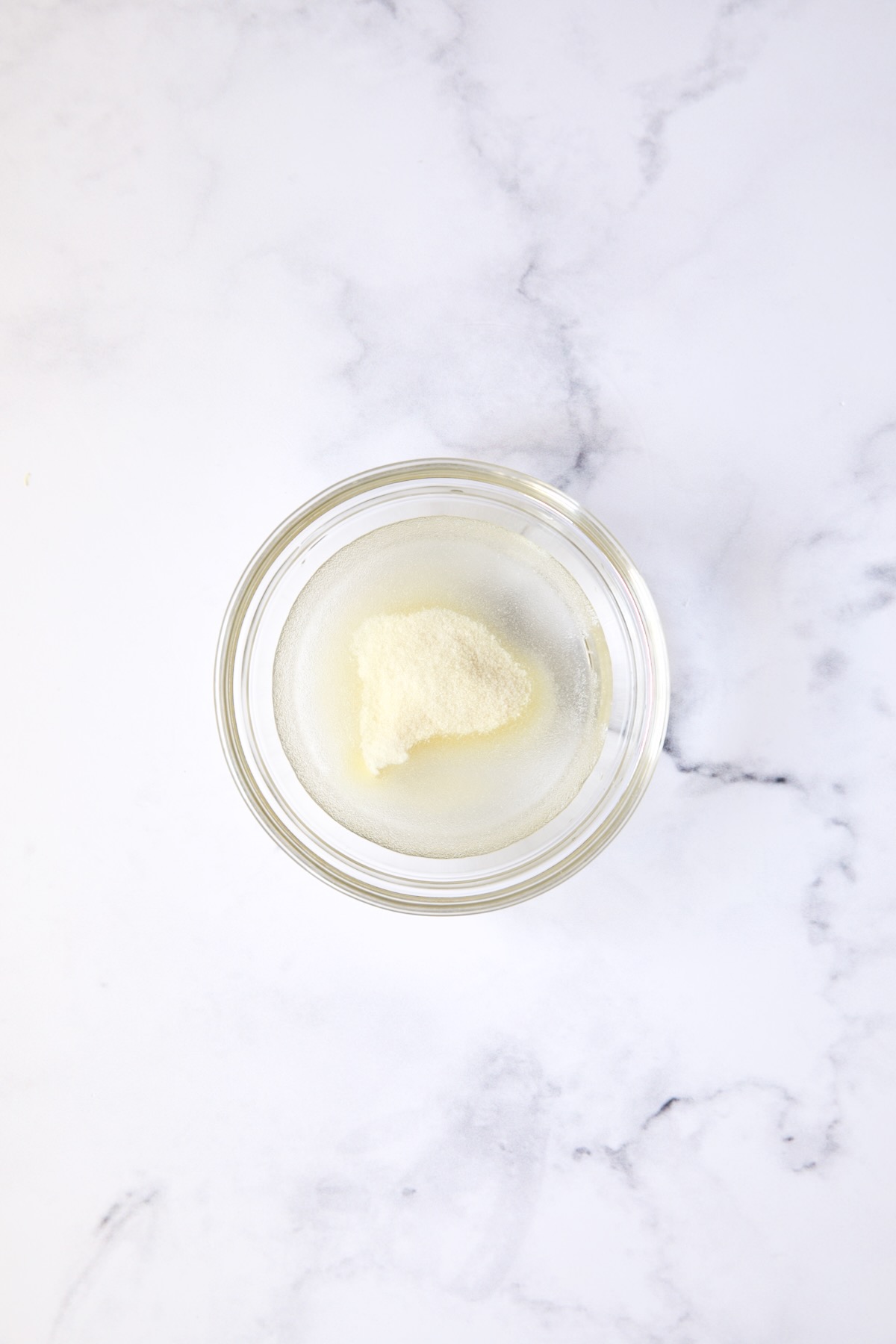 Gelatin powder in water in glass bowl.
