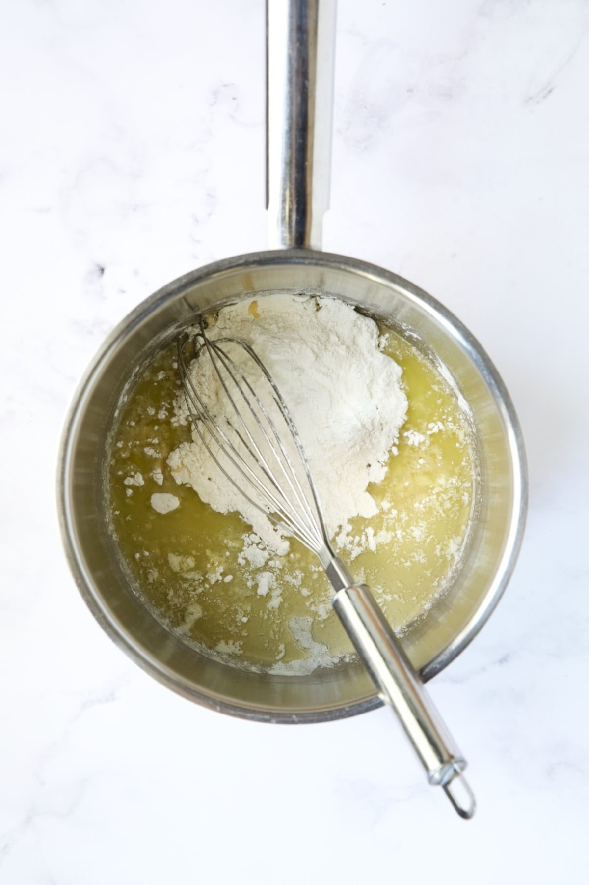 Flour added to butter in stainless steel saucepan with wire whisk.