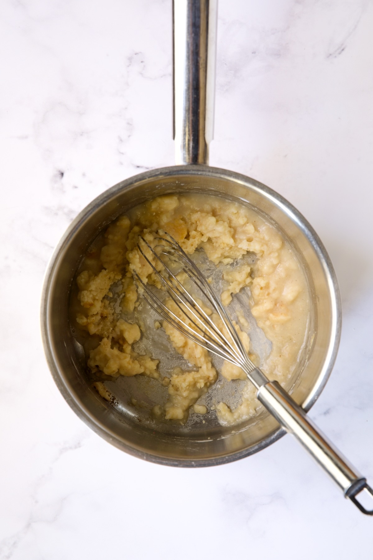 Whisk stirring wine into flour and butter combination in stainless steel saucepan.