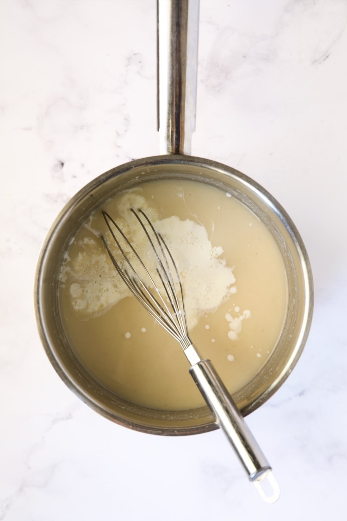 Sauce in stainless steel saucepan with cream added.