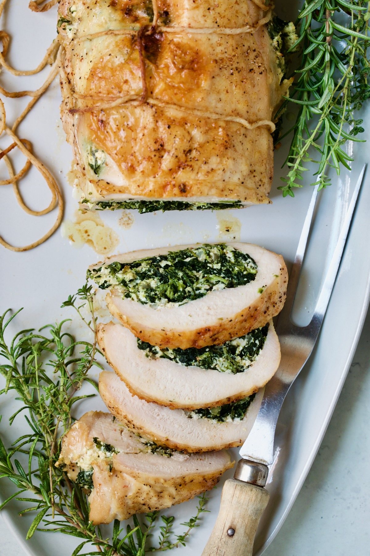 Spinach and Ricotta Stuffed Turkey Breast with Garlic - Herb Sauce showing filling garnished with fresh herbs.