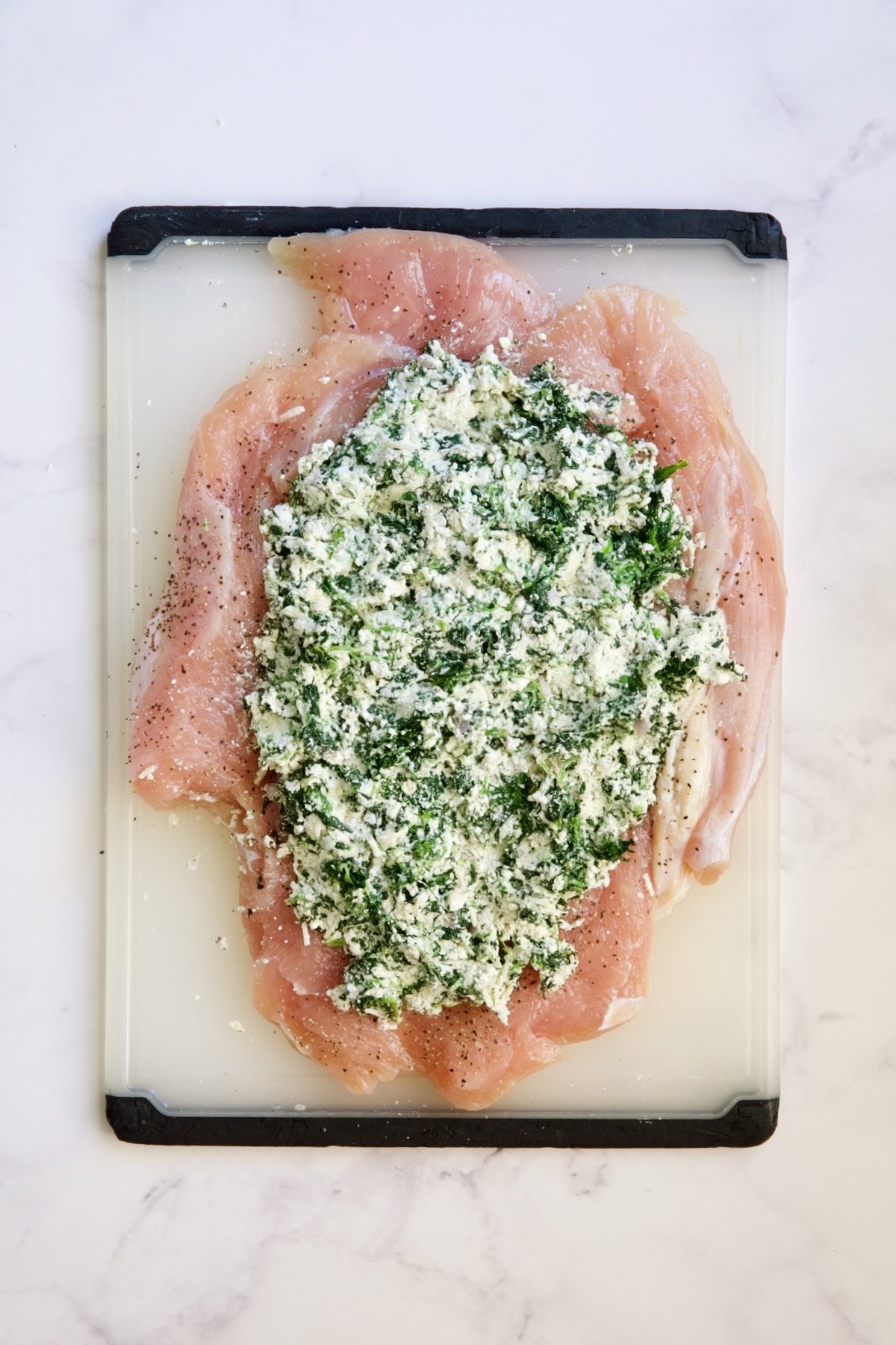 Butterflied turkey breast with filling on it before being rolled and tied.