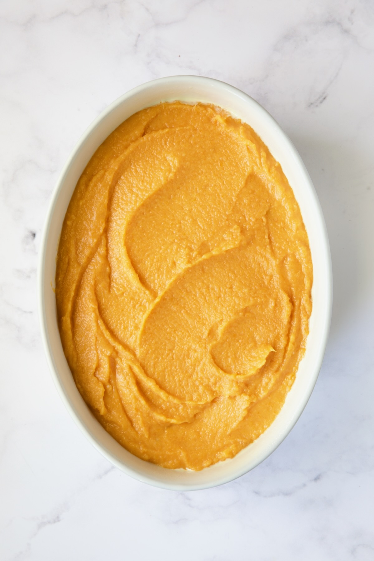 Souffle in white oval baking dish before pecan streusel topping gets added.