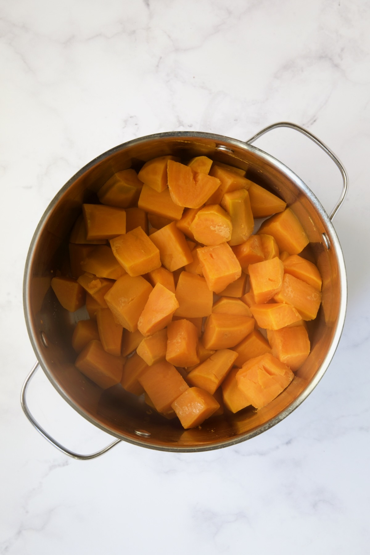 Cooked sweet potatoes in stainless steel pot.