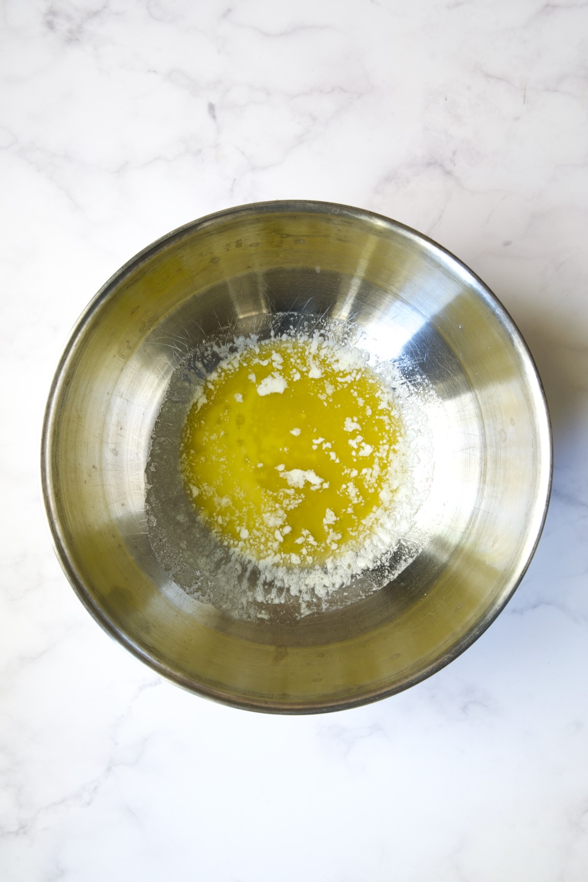 Melted butter in stainless steel bowl.