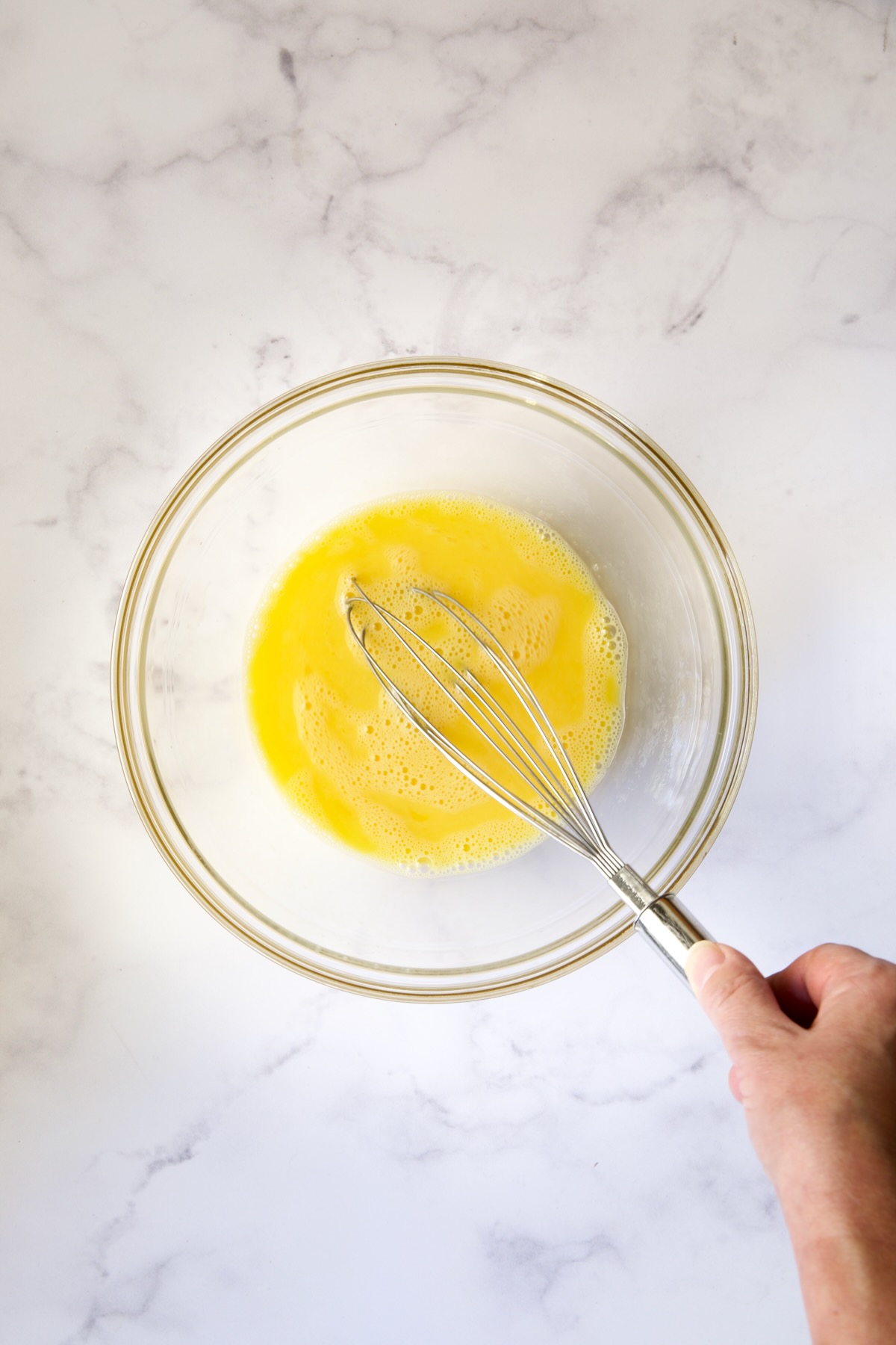 Eggs being beaten in glass bowl.