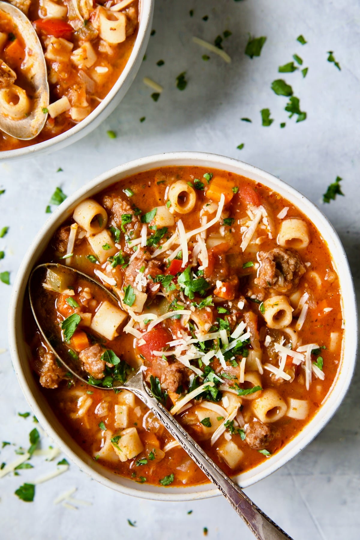 Bowl of Italian Sausage Soup with soup spoon scooping some out.