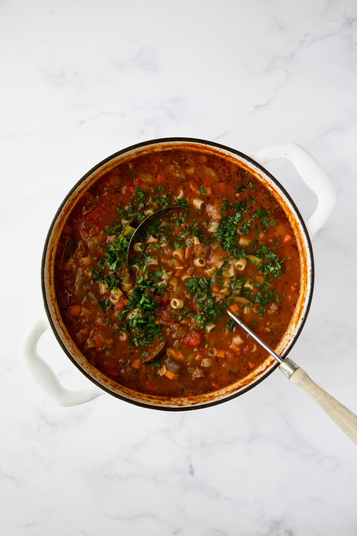 Soup in white Dutch oven with soup ladle.