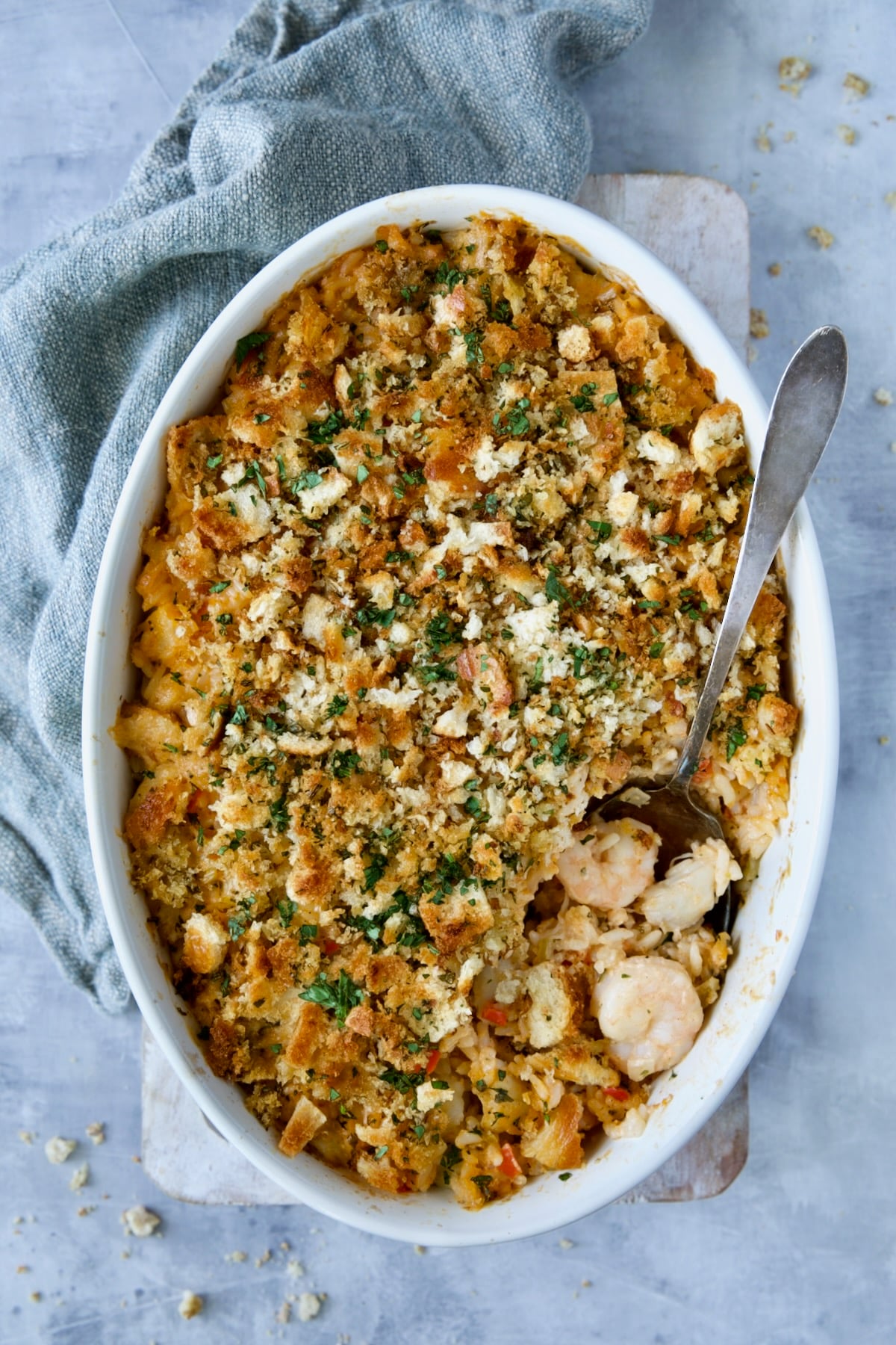 Shrimp and Crab Seafood Casserole in white baking dish with serving spoon scooping up shrimp and crab.