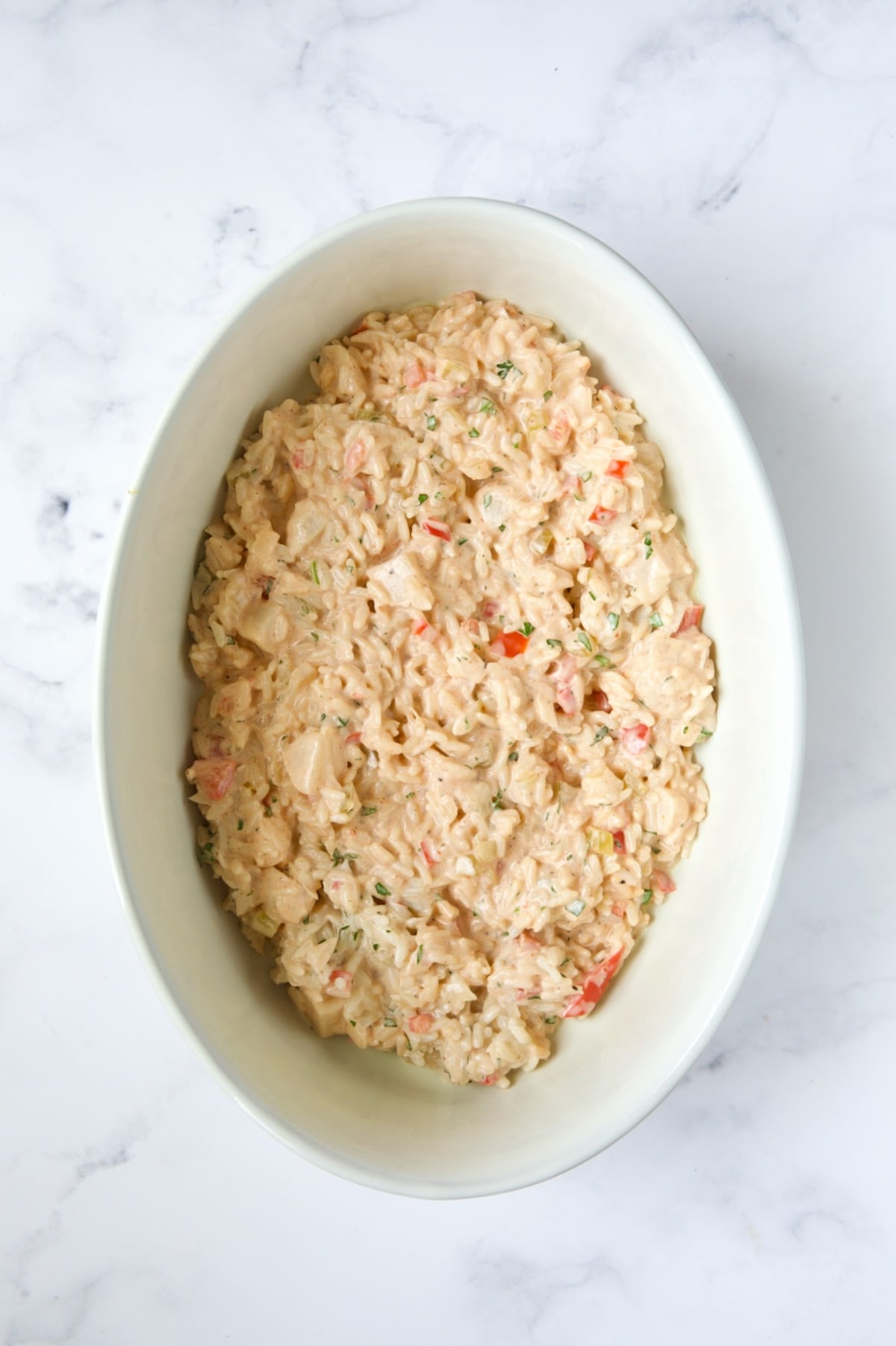 Layer of casserole in white oval baking dish.