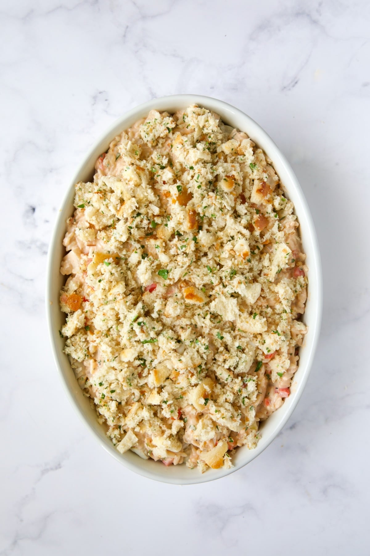 Assembled casserole in white baking dish with breadcrumb topping.