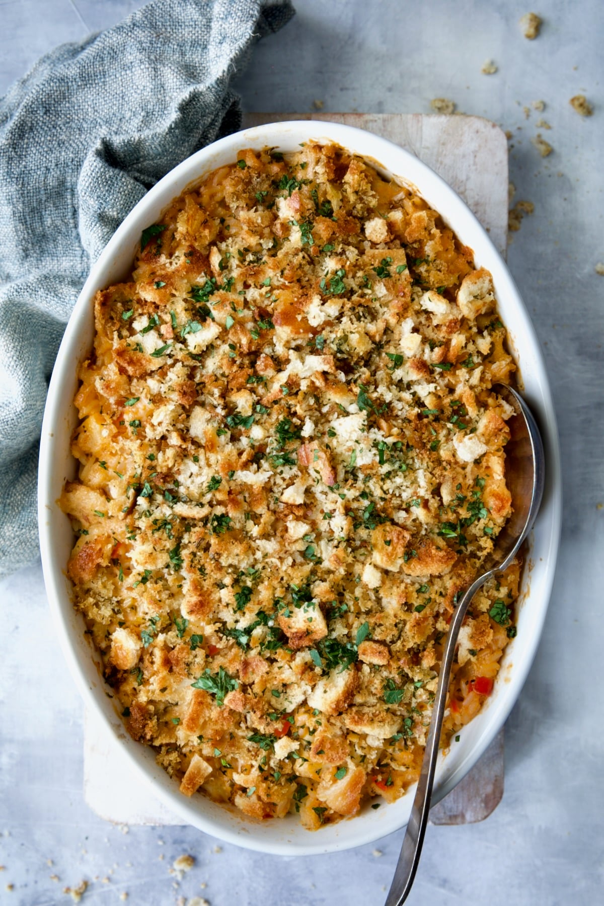 Baked Shrimp and Crab Seafood Casserole on blue background with blue napkin and serving spoon.