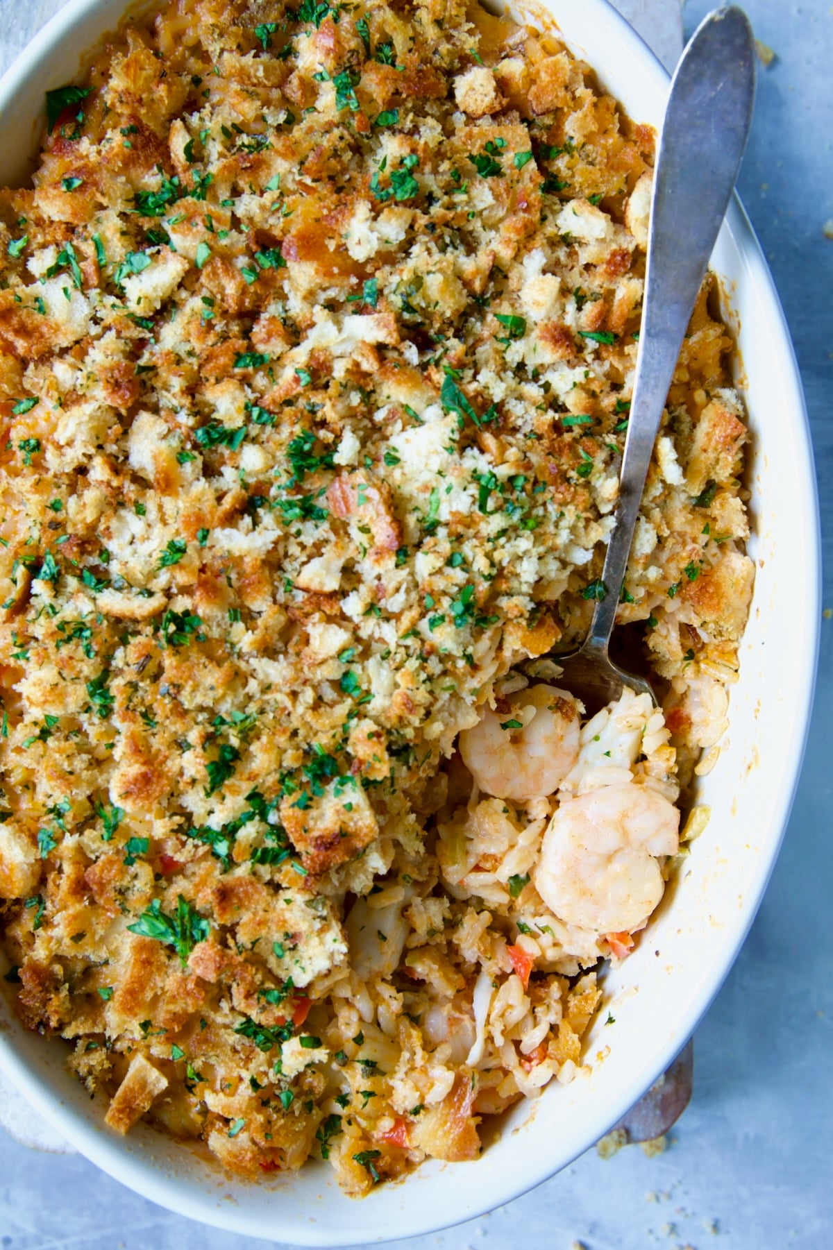 Shrimp and Crab Seafood Casserole in baking dish with serving spoon scooping some of the casserole out.