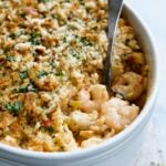 Shrimp and Crab Seafood Casserole in white baking dish with serving spoon scooping up shrimp and crab.