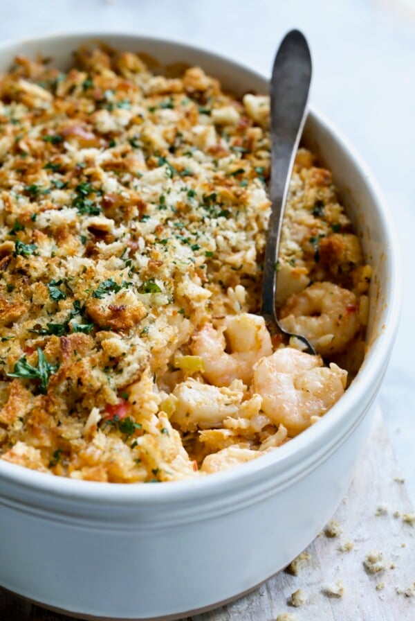 Shrimp and Crab Seafood Casserole in white baking dish with serving spoon scooping up shrimp and crab.