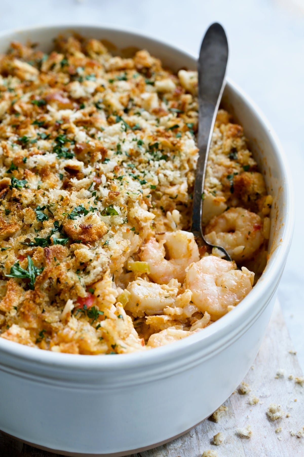 Shrimp and Crab Seafood Casserole in white baking dish with serving spoon scooping up shrimp and crab.