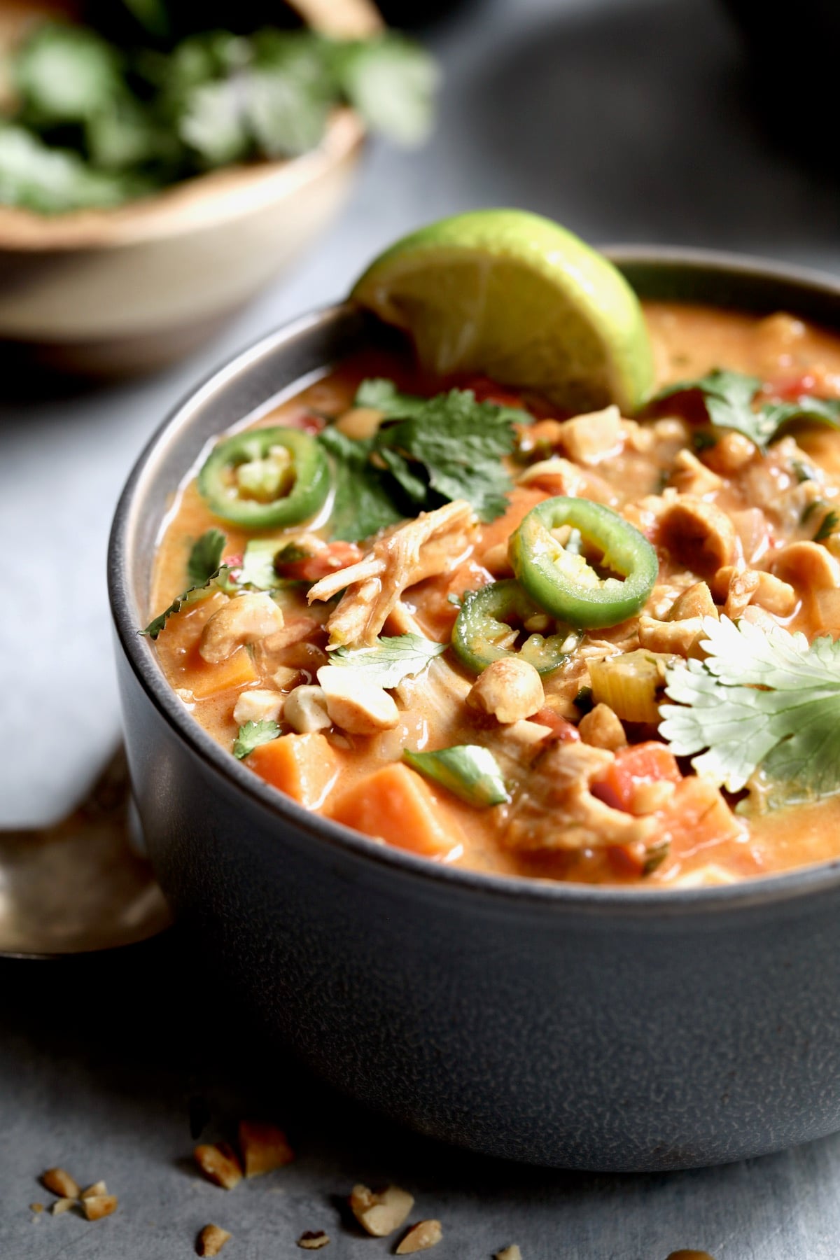 One serving of Spicy Chicken, Sweet Potato and Peanut Soup in gray bowl.