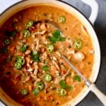 Spicy Chicken, Sweet Potato and Peanut Soup garnished with cilantro and jalapeno slices in white Dutch oven.