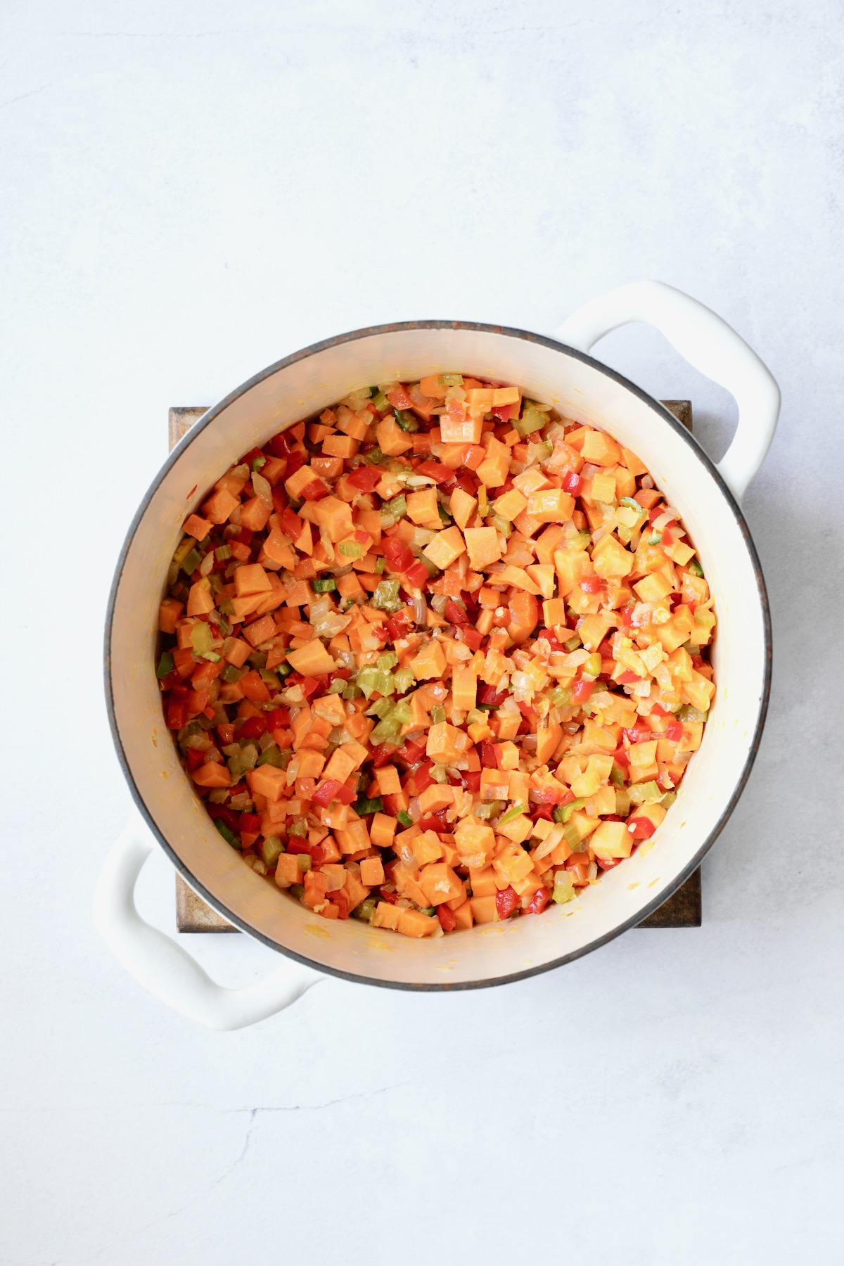Vegetables for soup in white Dutch oven.