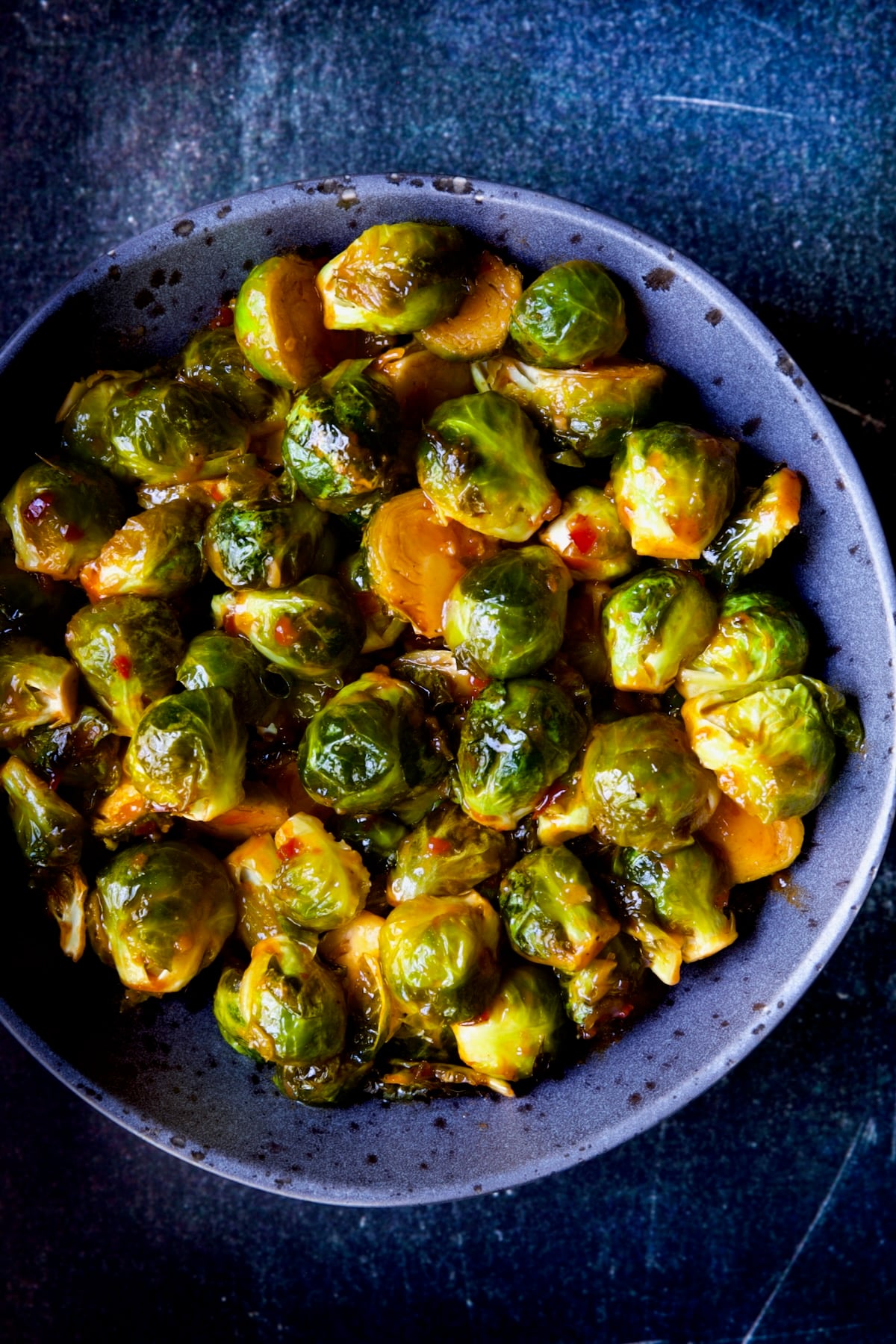 Sriracha Sweet Chili Roasted Brussels Sprouts in gray speckled bowl.