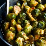 Sriracha Sweet Chili Roasted Brussels Sprouts in gray speckled bowl with serving spoon.
