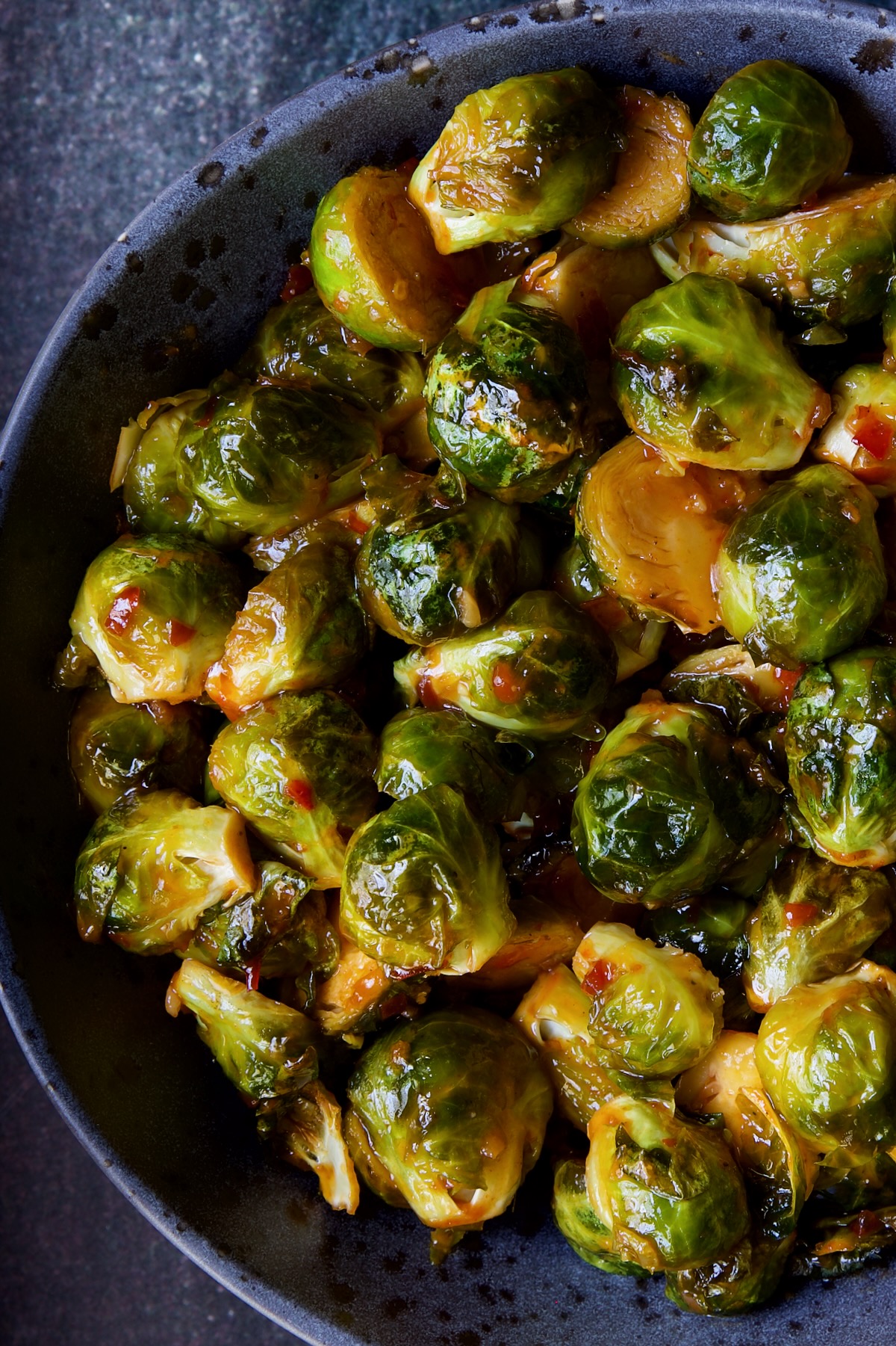 Sriracha Sweet Chili Roasted Brussels Sprouts in gray speckled bowl.