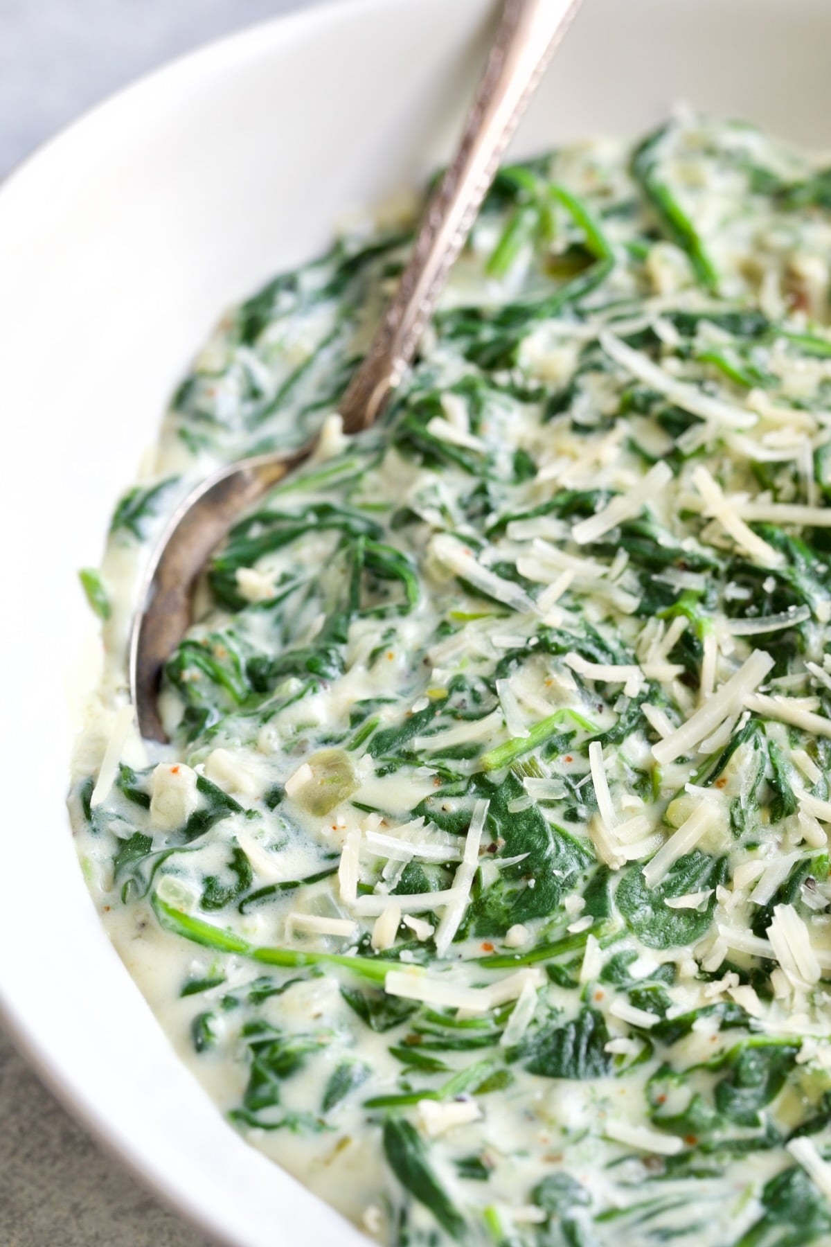 Steakhouse Creamed Spinach in white oval bowl with serving spoon.