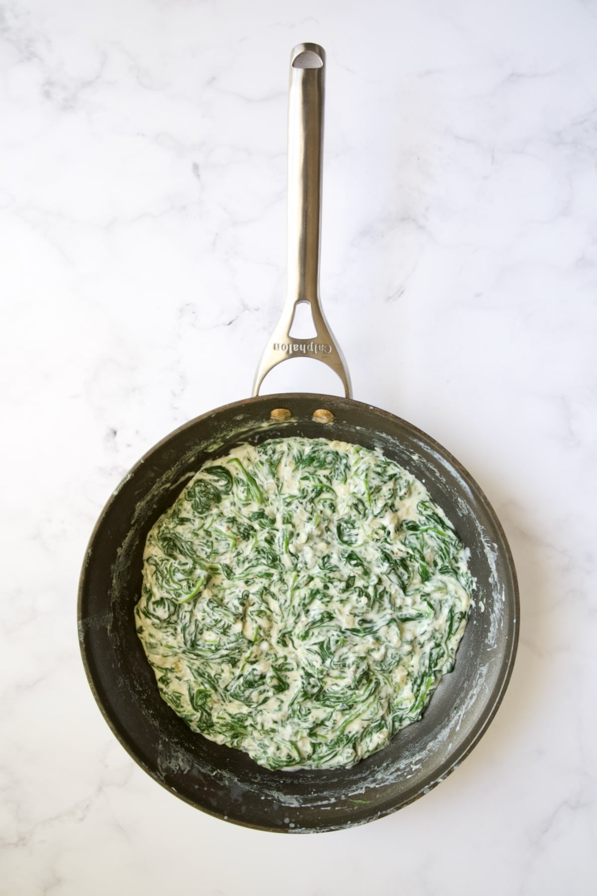Completely incorporated wilted baby spinach in cheese sauce in nonstick skillet.