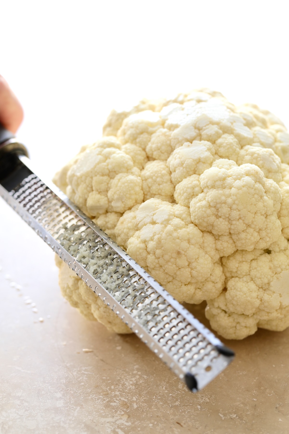 Microplane grating brown spots off head of cauliflower.