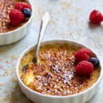 Classic Creme Brulee for Two garnished with red raspberries and blueberries.