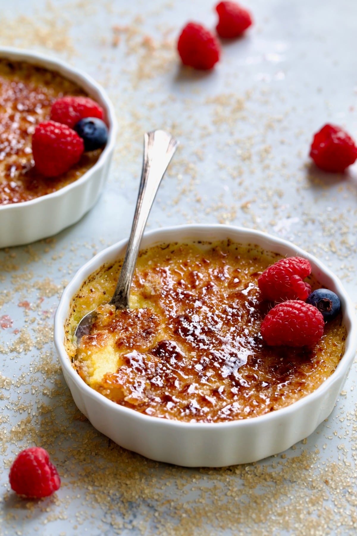 Classic Creme Brulee for Two garnished with red raspberries and blueberries.