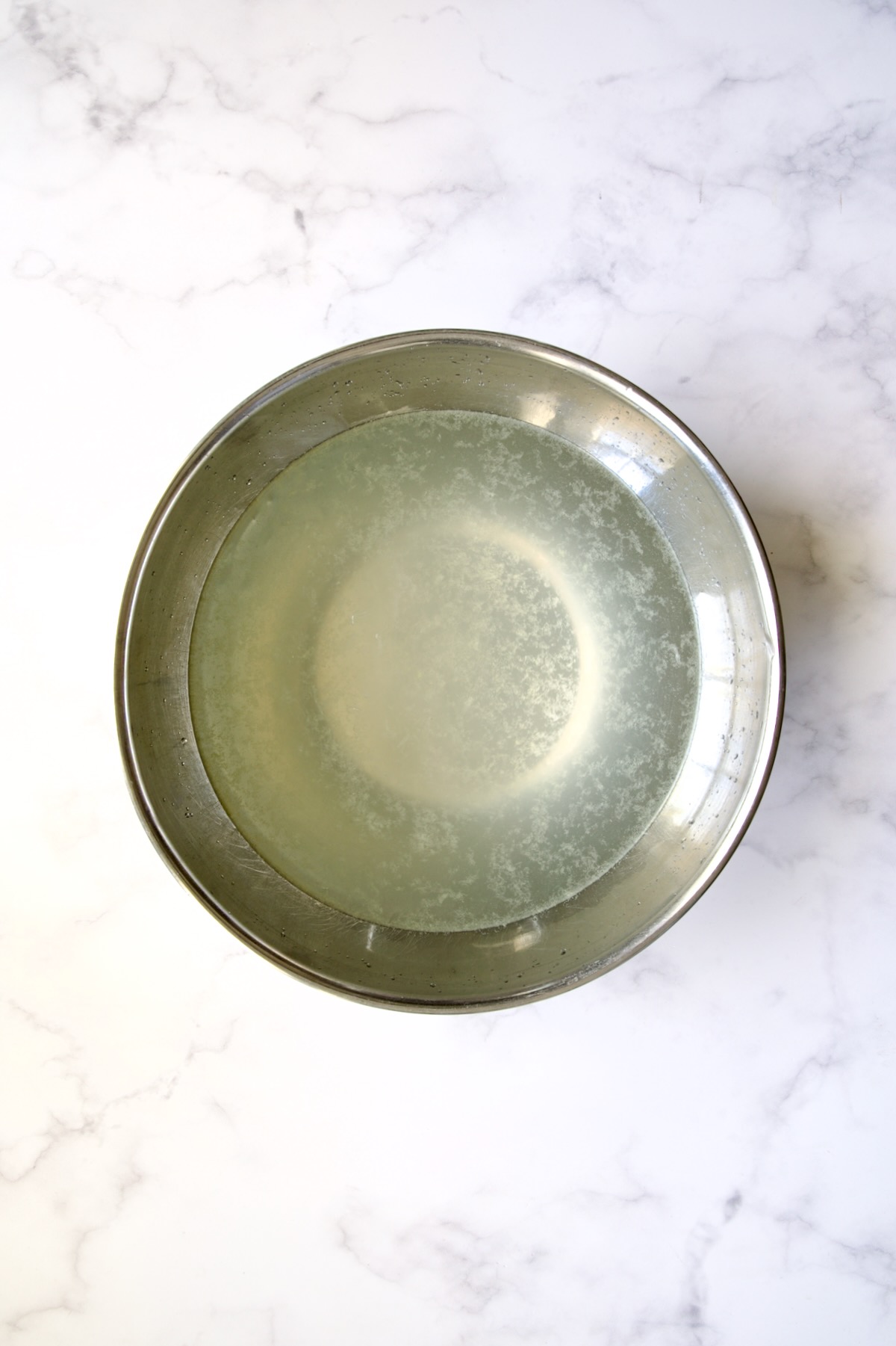 Stainless steel bowl with lemon water in it.