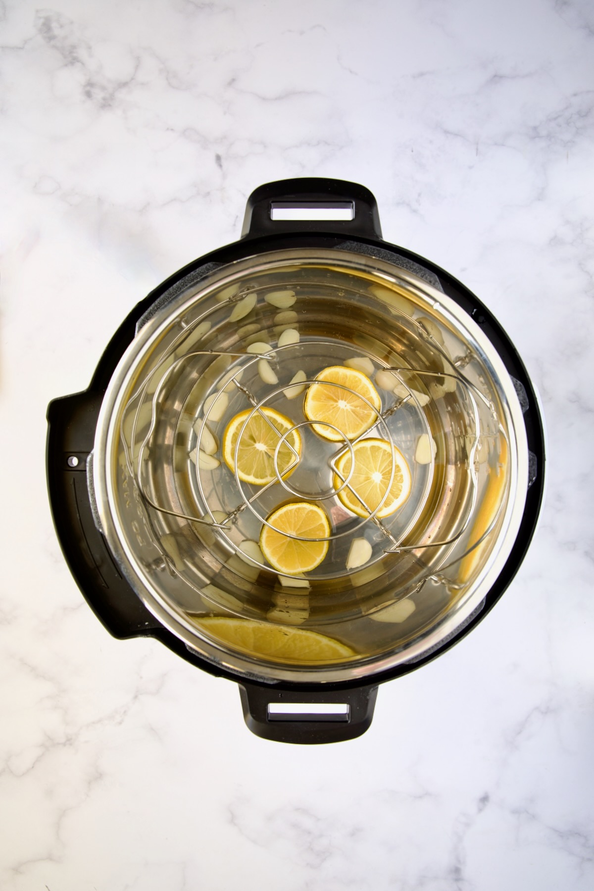 Four lemon slices and sliced garlic in Instant Pot.