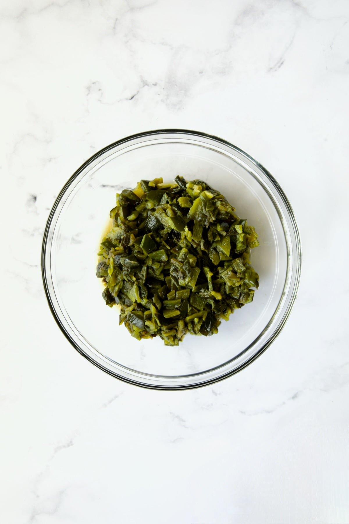 Chopped, roasted poblano peppers in glass bowl.