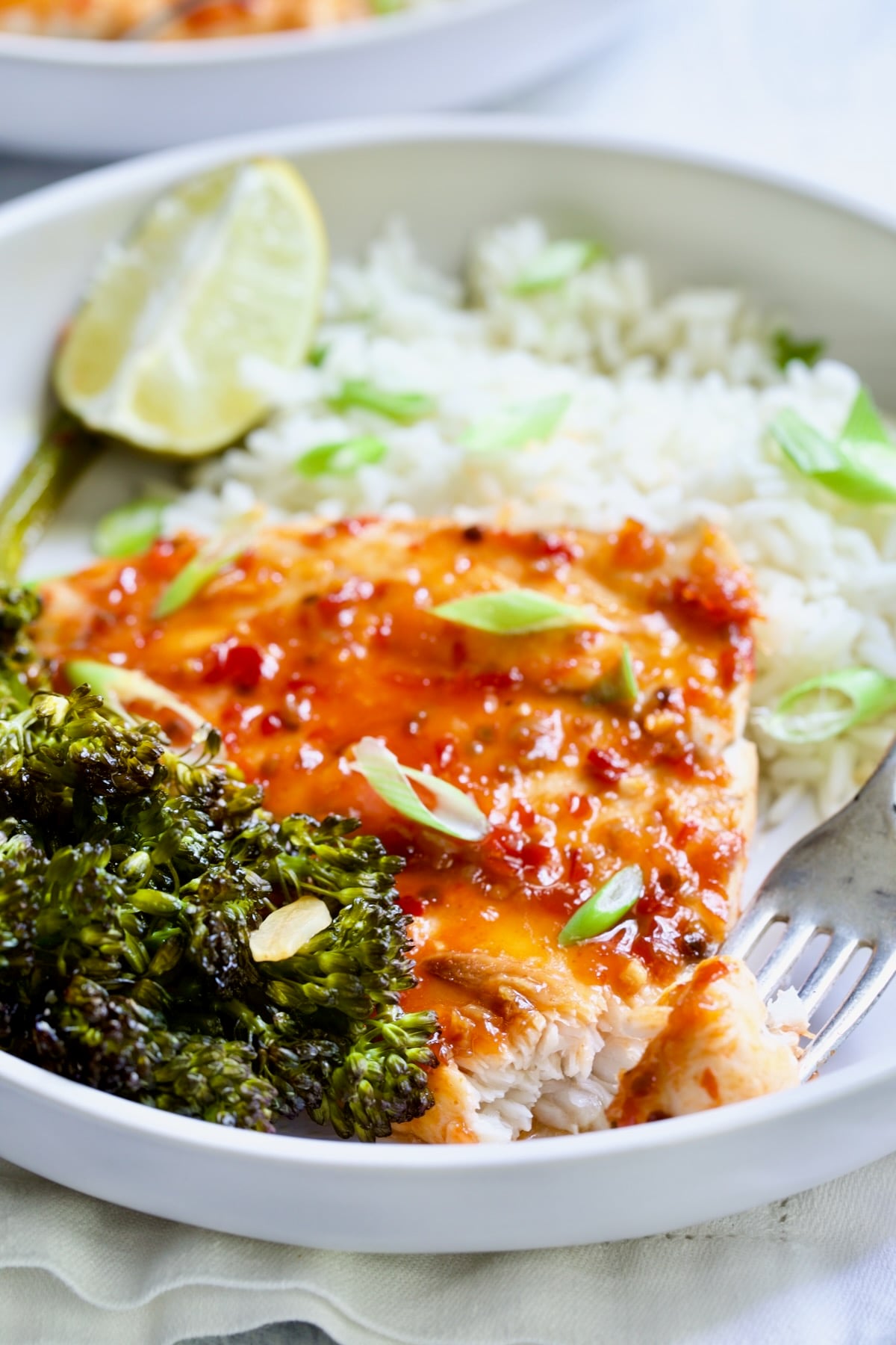 Sheet Pan Thai Baked Fish with Broccolini on white plate with fork.