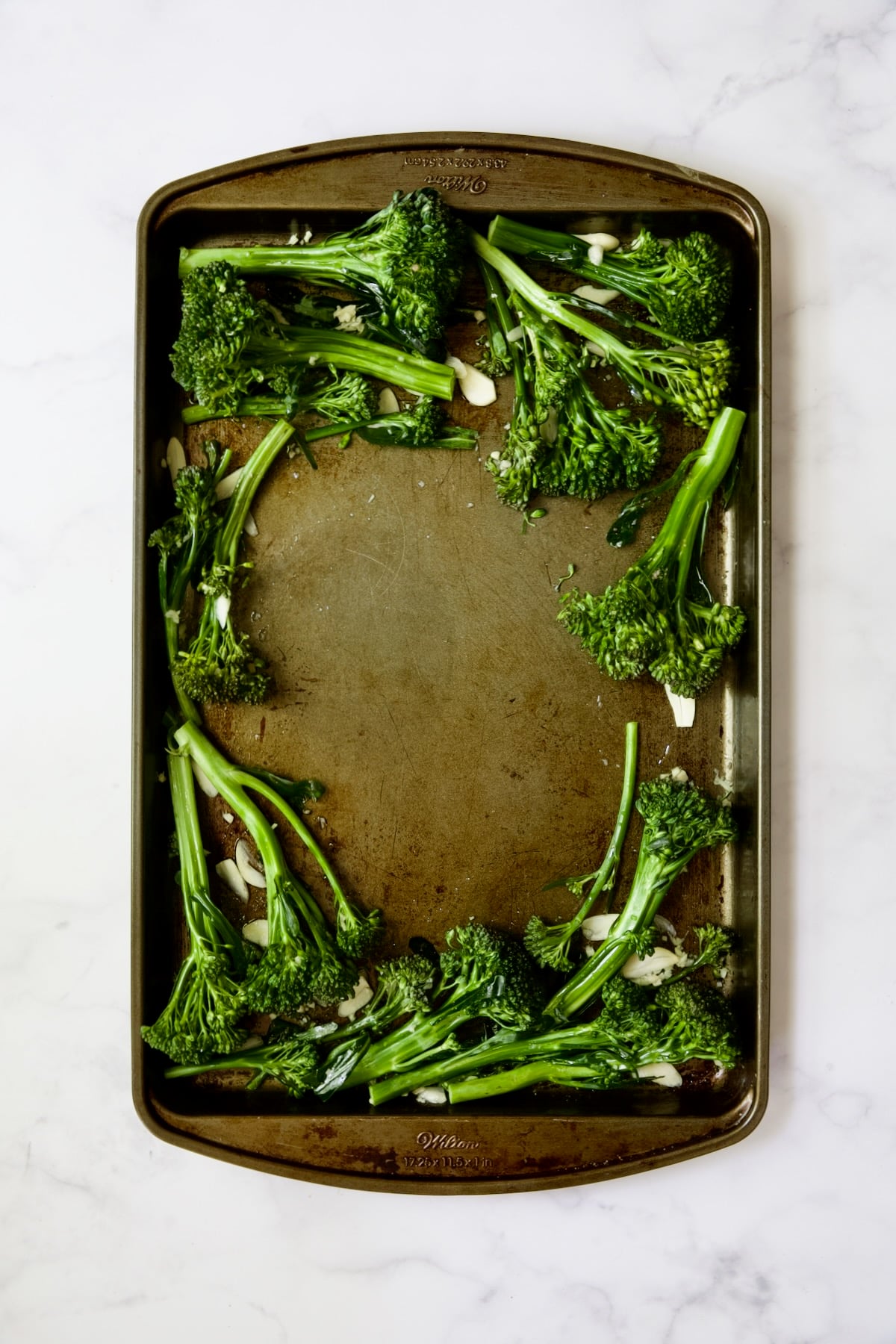 Broccolini and garlic on rimmed sheet pan.