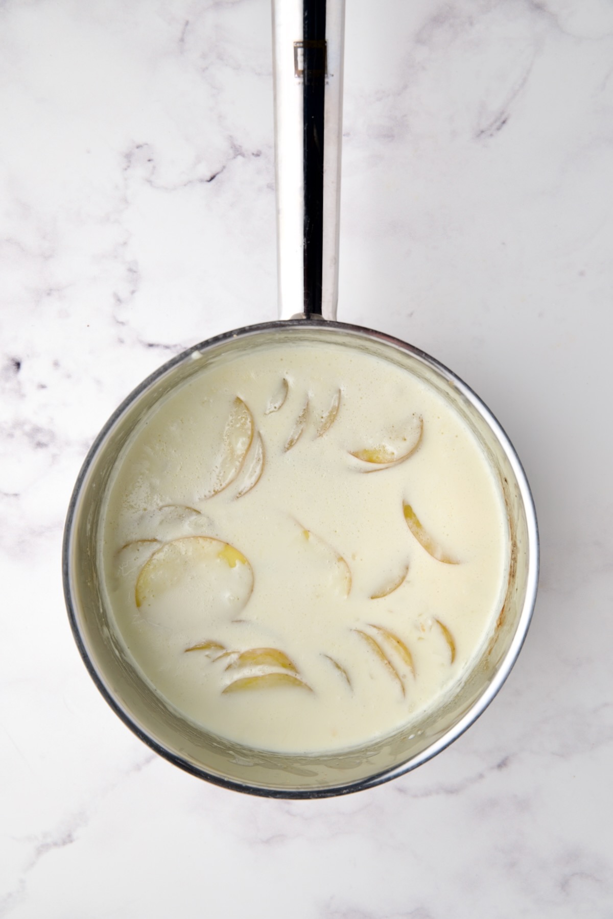Cooked Yukon Gold potatoes in stainless steel saucepan with cream.