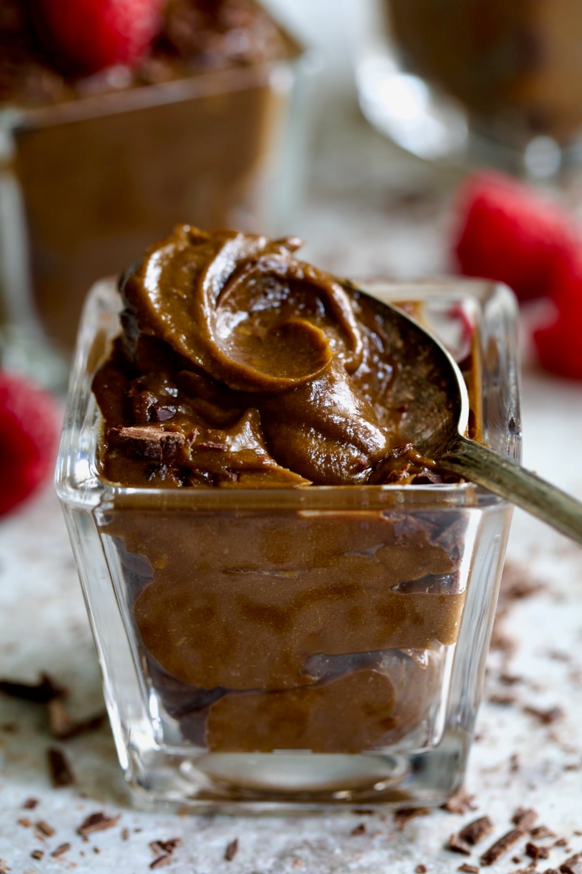 Spoon lifting some of the Chocolate Avocado Mousse out of a square dessert glass.