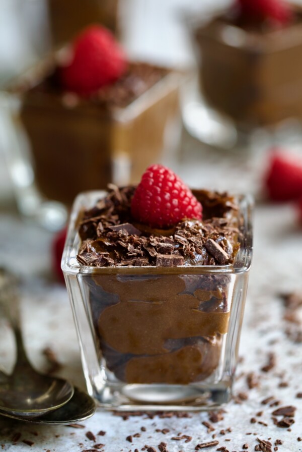Chocolate Avocado Mousse in square dessert glass garnished with fresh raspberry.