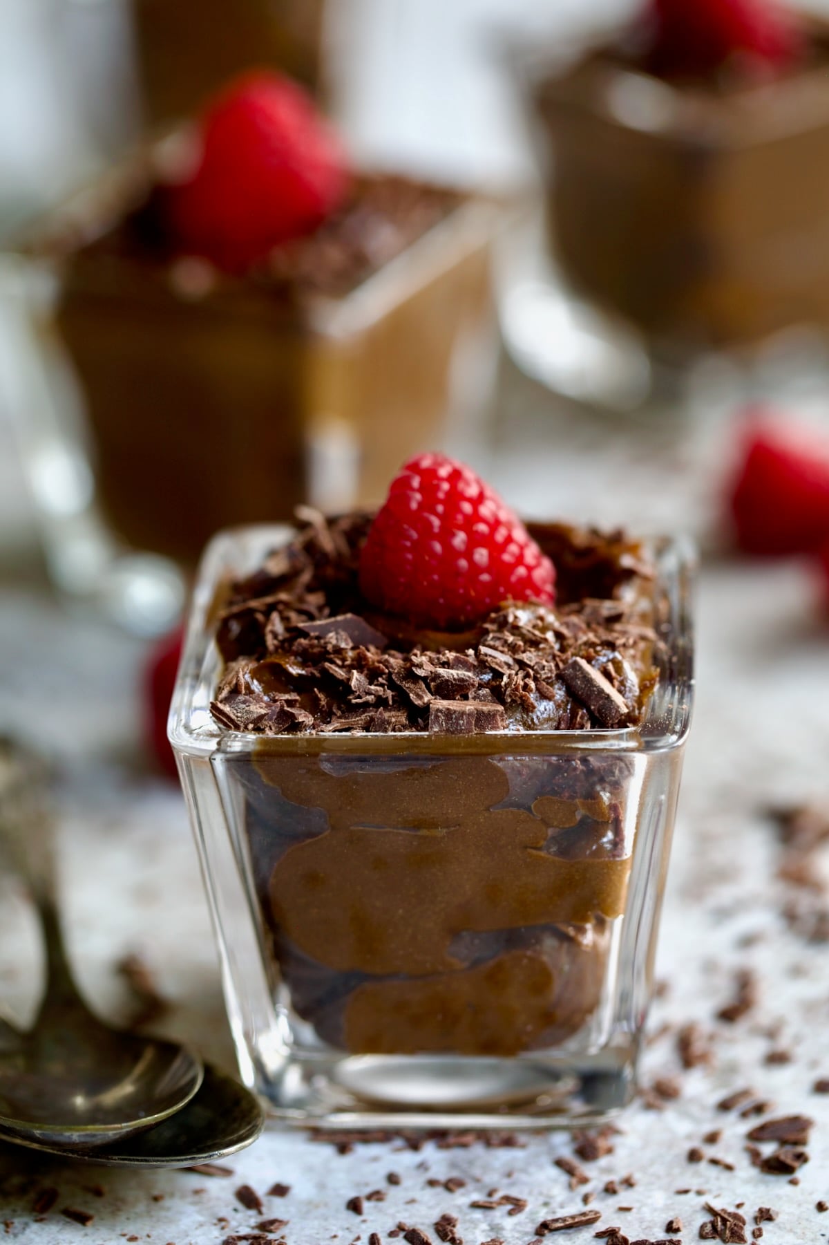 Chocolate Avocado Mousse in square dessert glass garnished with fresh raspberry.