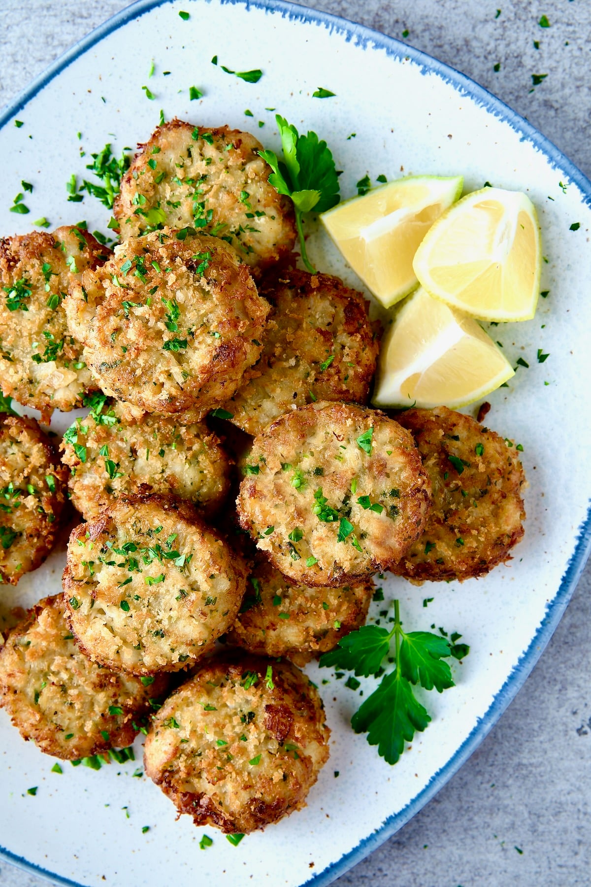 Maryland-Style Crab Cakes on platter with parsley and lemon wedges.