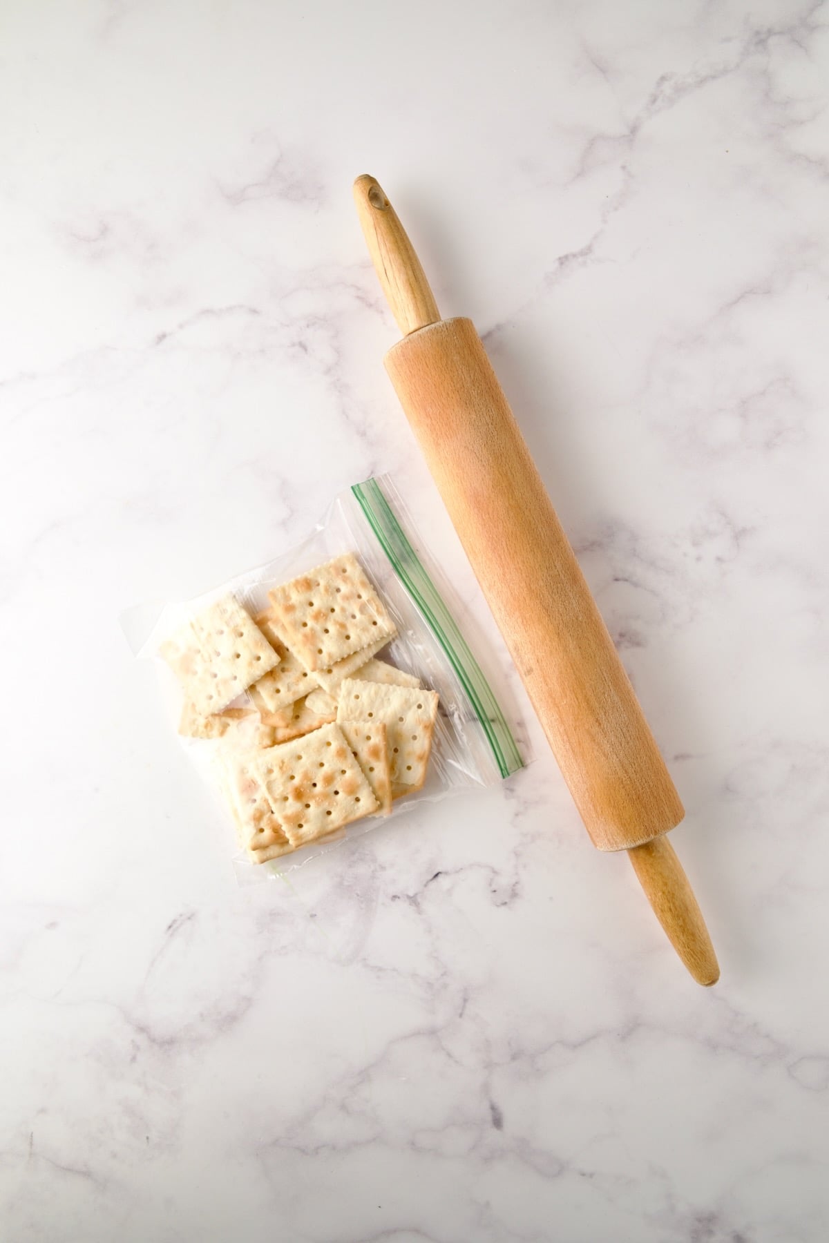 Saltine crackers in sandwich bag with rolling pin before being crushed.