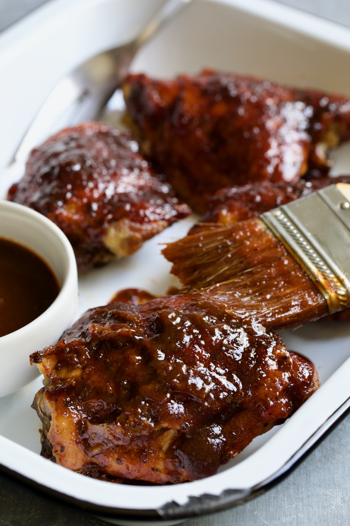 Baked BBQ Chicken Thighs in white enamel serving tray.