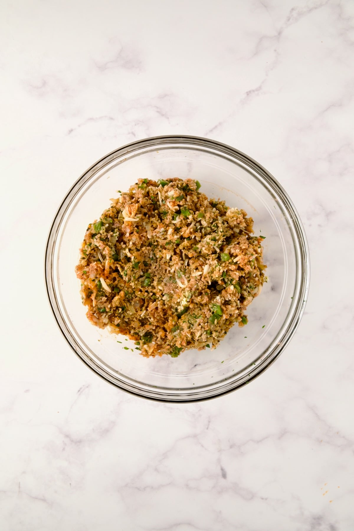 Ingredients for meatloaf mixed together in glass bowl before ground meats are added.