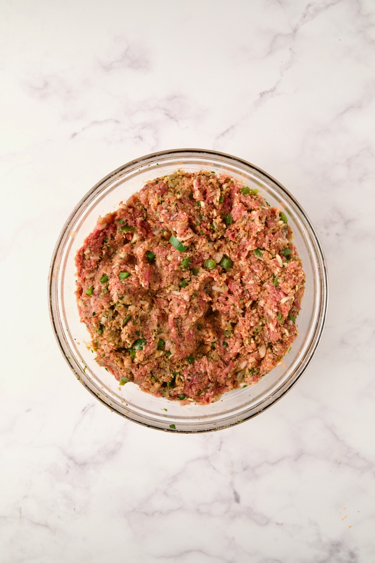 Ingredients for meatloaf fully combined in glass bowl before being placed on sheet pan.